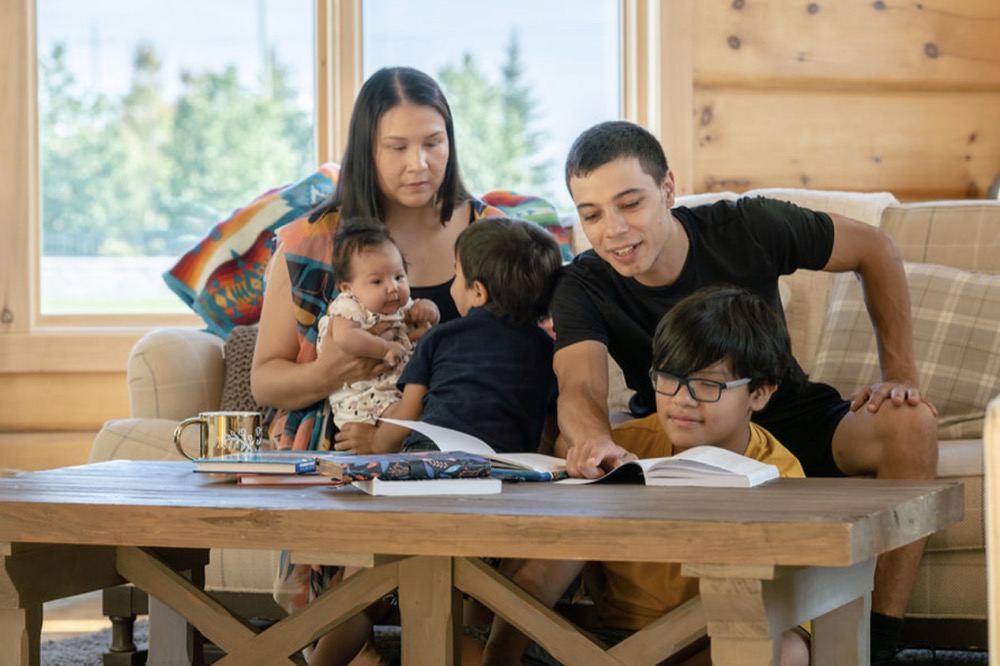 A family in a wooden home with an infant and two children.